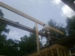Carpenter setting a ridge beam over a new addition frame — Ice Dam Removal by Roofing Brothers in Dickinson