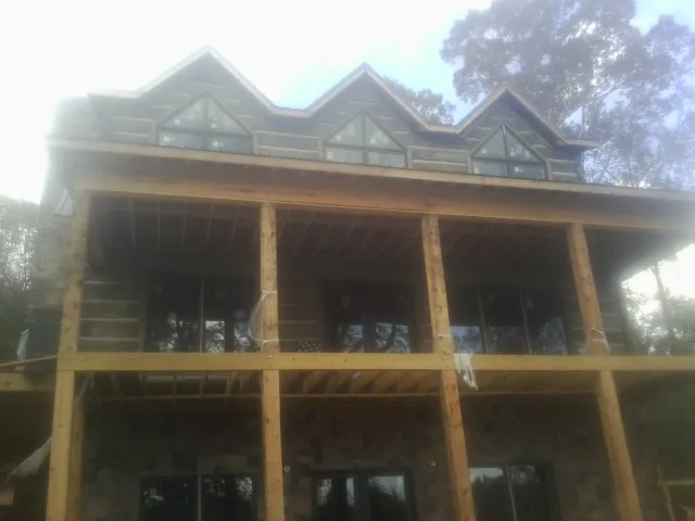 Dormers and porch framing on a large log home under construction — Roof Coating work by our crew in Dickinson