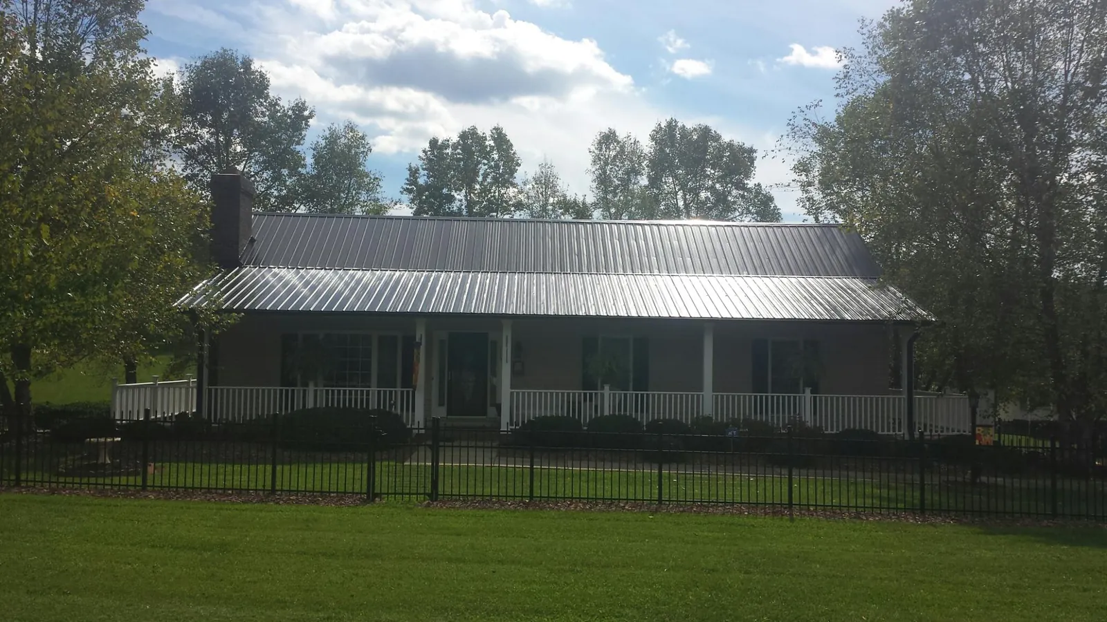 Gray metal roof on a brick ranch with a full width front porch — Gutter Guard Installation work by our crew in Dickinson