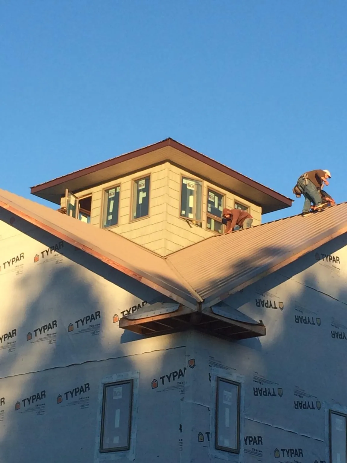 Roofers working around a rooftop cupola on a new metal roof at sunset — Roof Waterproofing in Dickinson by Roofing Brothers